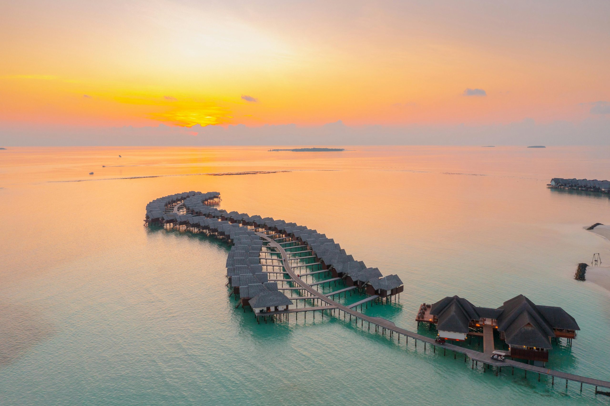 A stunning aerial view of overwater bungalows during sunset in Maldives, highlighting serene ocean views.